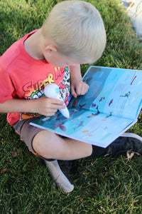 A boy reading the Discover Talking Book by pointing the talking pen to an illustration listening to the sound effect while learning S.T.E.M. facts screen free. 