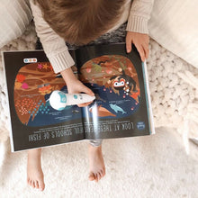 Load image into Gallery viewer, A boy reading the Discover Talking Book by pointing the talking pen to an illustration listening to the dolphin sound effect while learning S.T.E.M. facts screen free. 